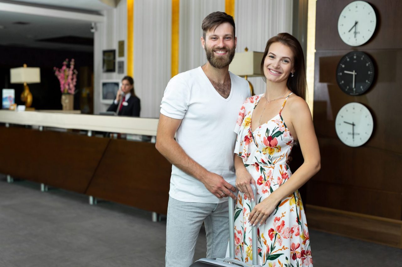 Un couple échange avec le personnel à la réception d’un hôtel libertin à Cannes.