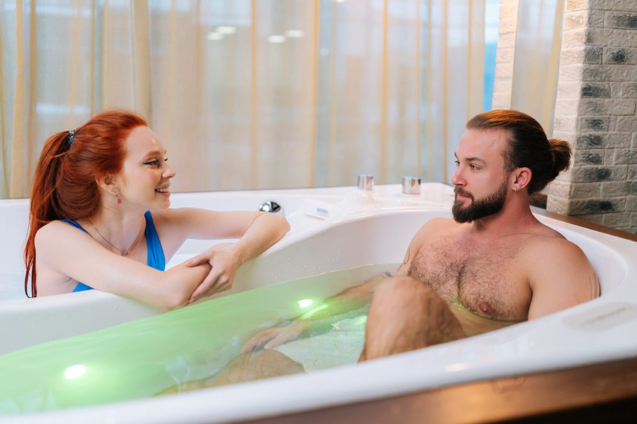 Couple vérifiant l’espace et le jacuzzi privatif d’une love room à Paris avant la réservation