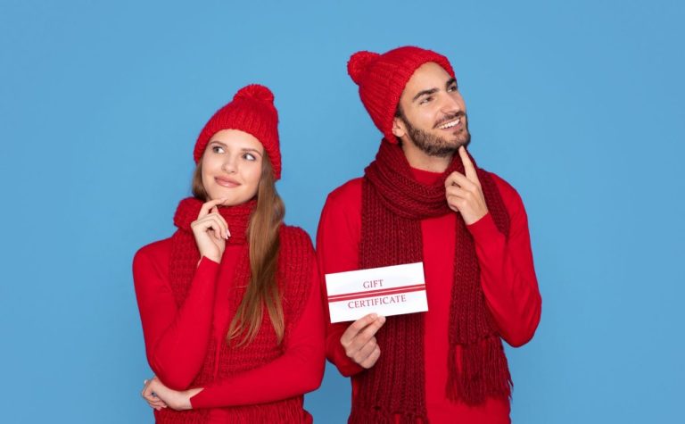 Un couple tient un bon cadeau pour une nuit romantique en love room à Grenoble.